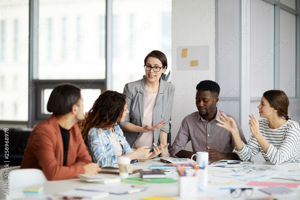 Portrait of modern female manager talking to multi-ethnic team during meeting in office, copy space Portrait of modern female manager talking to multi-ethnic team during meeting in office, copy space