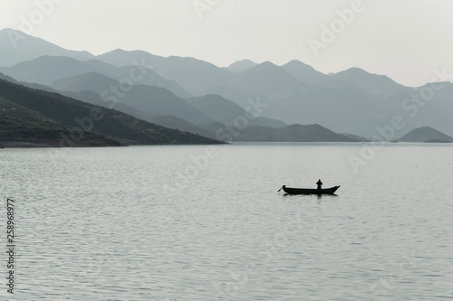 Silhouette of a fisherman in small boat in lake, Albania
