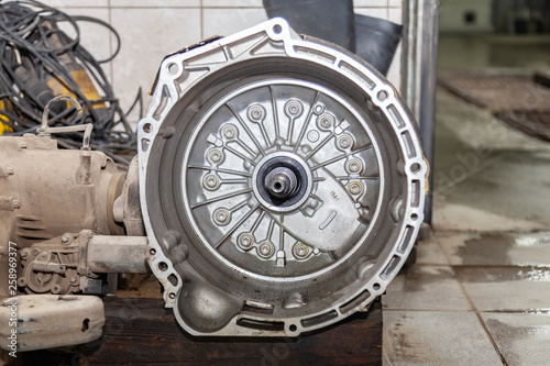 A side view of a silver gearbox taken from a car in a vehicle repair workshop. Auto service industry.