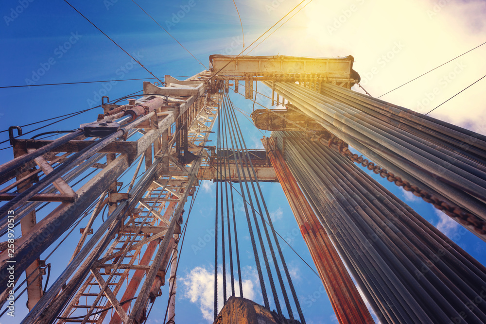Obraz premium Onshore land rig in oil and gas industry. Oil drilling rig against a blue sky with clouds