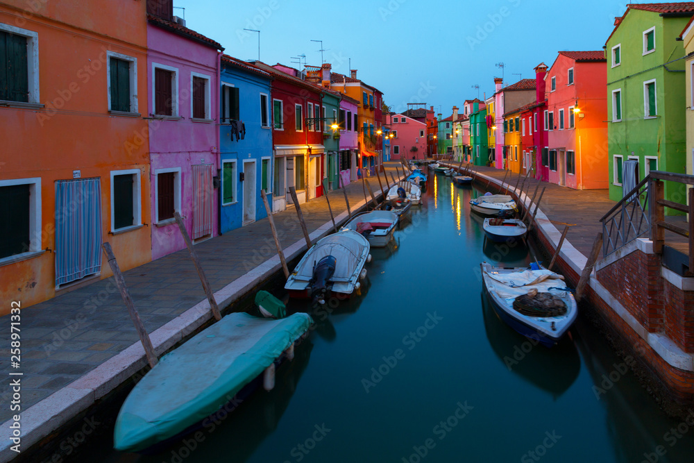 Colorful houses and boats at night in Burano, Venice Italy.