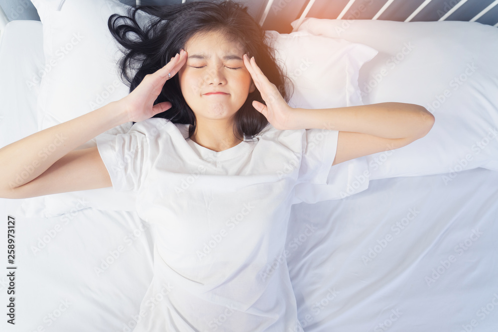 Woman stretching in bed after waking up, back view. Woman sitting near the big white window while stretching on bed after waking up with sunrise at morning, back view. Woman stretching in bed after waking up, back view. Woman sitting near the big white window while stretching on bed after waking up with sunrise at morning, back view.