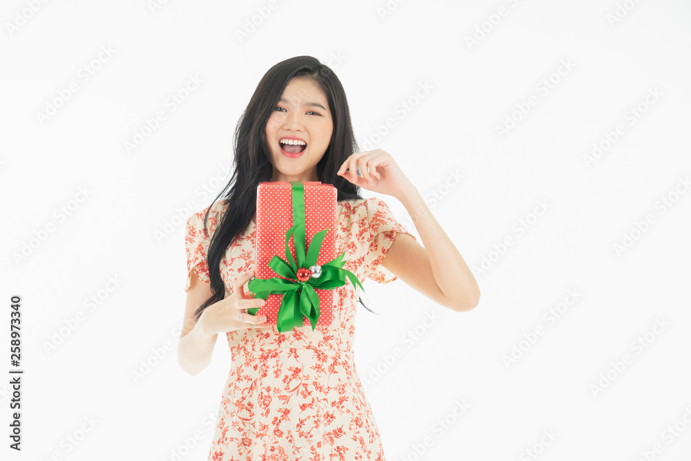Curious woman in red dress rejoicing her birthday or new year gift box. Young woman holding gift box with red bow being excited and surprised holiday present isolated white background Curious woman in red dress rejoicing her birthday or new year gift box. Young woman holding gift box with red bow being excited and surprised holiday present isolated white background