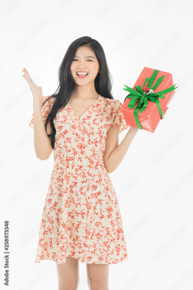Curious woman in red dress rejoicing her birthday or new year gift box. Young woman holding gift box with red bow being excited and surprised holiday present isolated white background Curious woman in red dress rejoicing her birthday or new year gift box. Young woman holding gift box with red bow being excited and surprised holiday present isolated white background