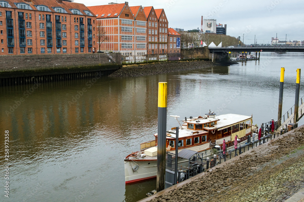 Fototapeta premium Pier with moored vessel on the banks of the River Weser in Bremen, Germany. March 2019