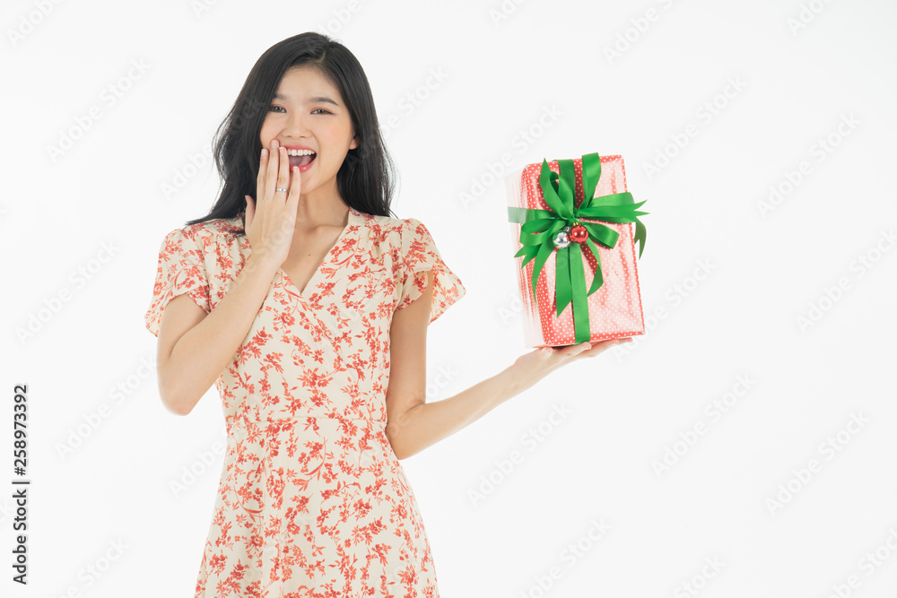 Curious woman in red dress rejoicing her birthday or new year gift box. Young woman holding gift box with red bow being excited and surprised holiday present isolated white background Curious woman in red dress rejoicing her birthday or new year gift box. Young woman holding gift box with red bow being excited and surprised holiday present isolated white background