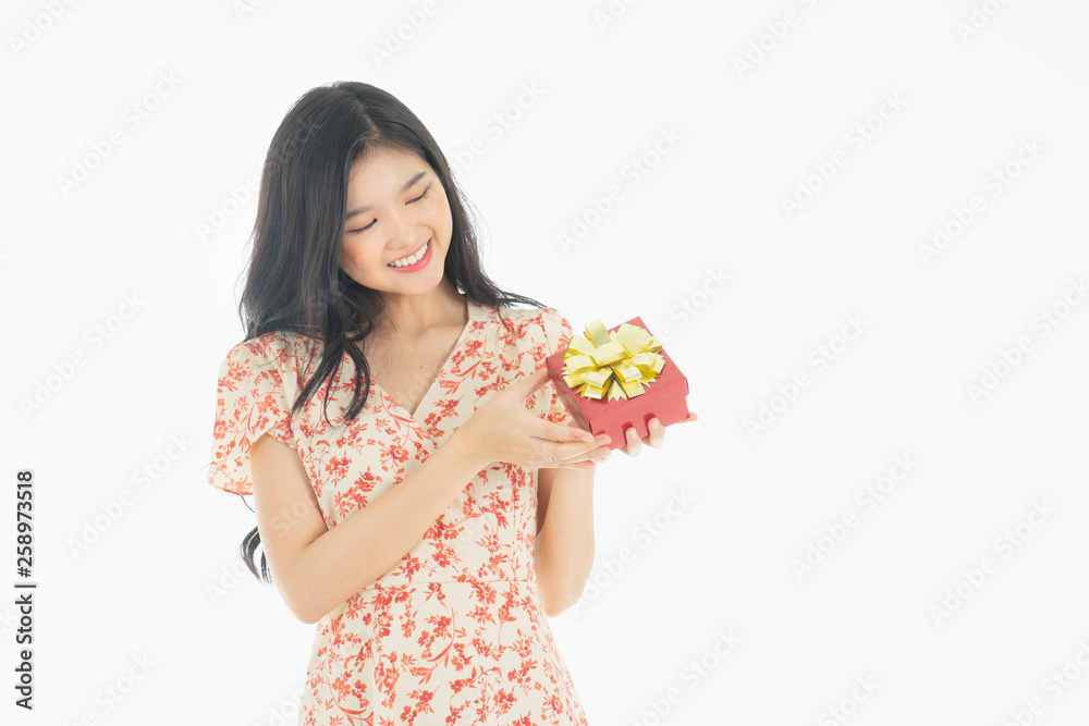 Curious woman in red dress rejoicing her birthday or new year gift box. Young woman holding gift box with red bow being excited and surprised holiday present isolated white background Curious woman in red dress rejoicing her birthday or new year gift box. Young woman holding gift box with red bow being excited and surprised holiday present isolated white background