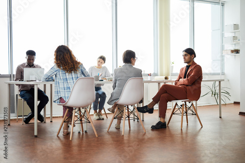 Multi-ethnic group of contemporary business people working at table in office, copy space