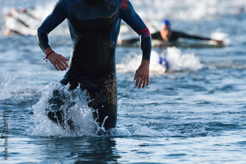 Quadro su tela Triathletes running out of the water on triathlon race