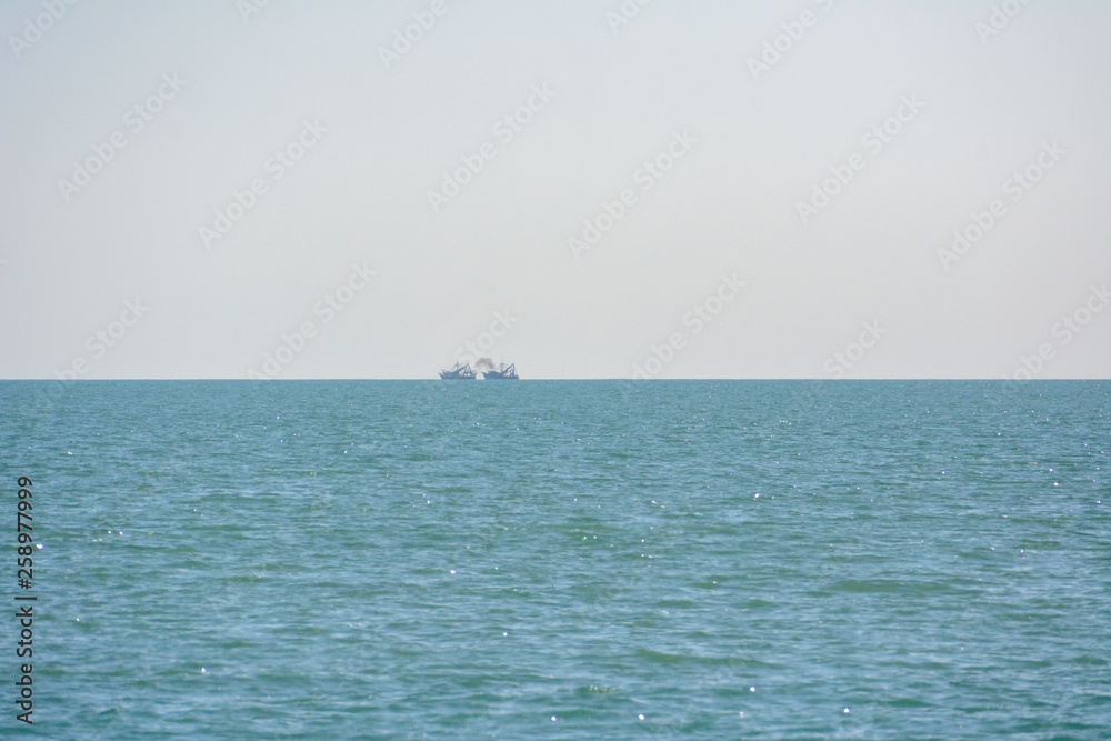 Fishing vessels with exhaust plume visible on the horizon in the Gulf of Mexico off the coast of Florida