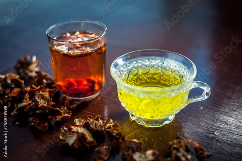 Raw organic amaltas or golden shower tree fruit on wooden surface with its extracted pulp in a glass along with water and green tea in a glass cup.Used for the treatment of worms in intestine.