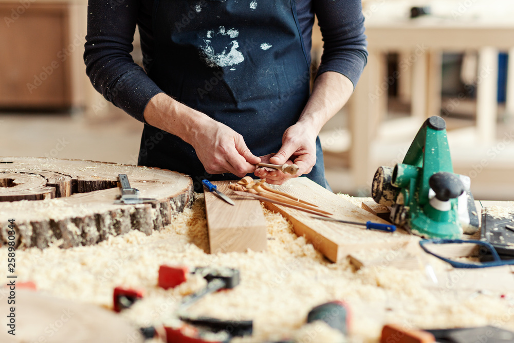 Hands of craftsman sanding handmade wooden hair sticks with