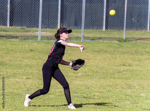 Fotografie Skilled teenage softball player releasing a quick throw after making a defensive catch in the outfield