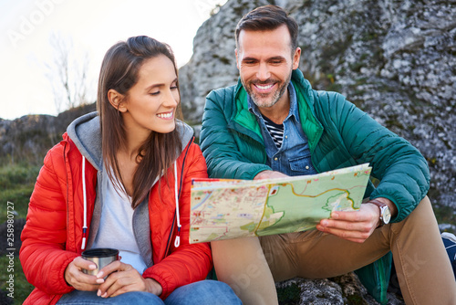 Happy couple on a hiking trip in the mountains taking a break looking at map photo