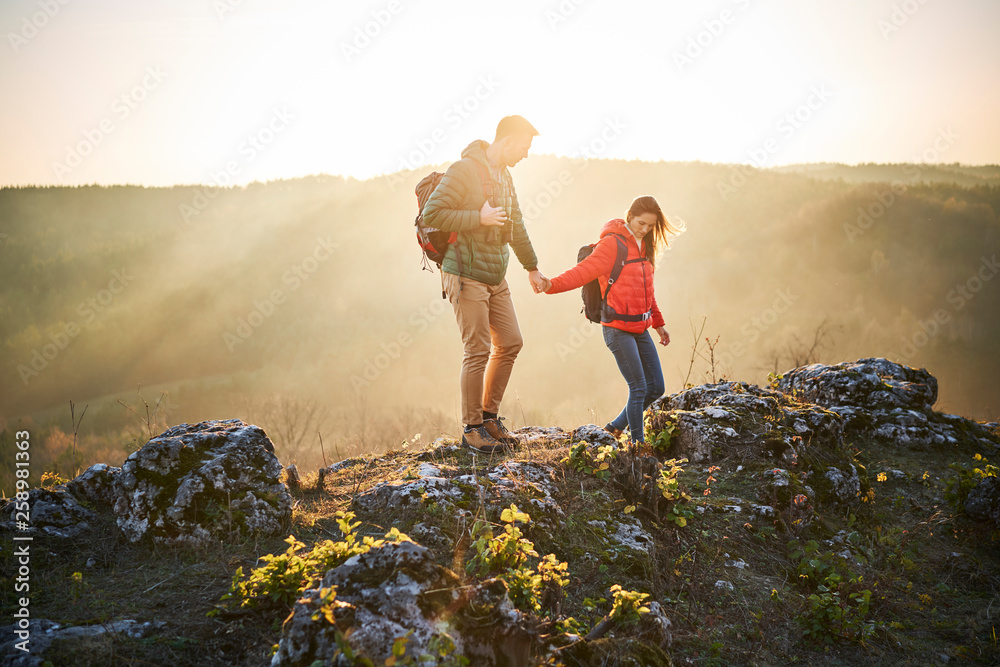 Couple hiking on rocks on sunny day