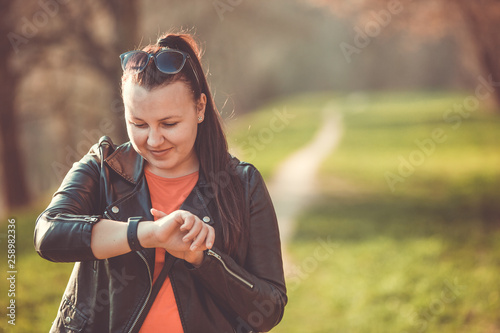 Pretty young brunette woman using smartwatch in outside (color toned image)