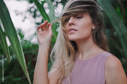 Portrait of young beautiful woman with closed eyes and long hair in tropical forest