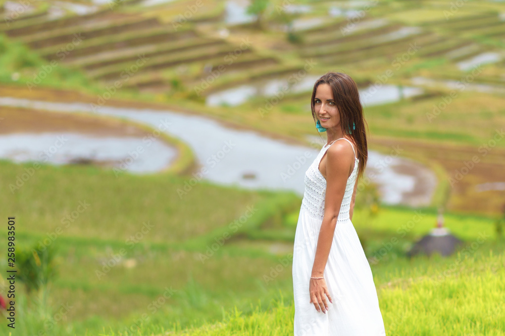 Tanned young woman posing on the background of rice fields. Close up Tanned young woman posing on the background of rice fields. Close up