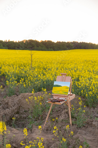 easel with paints and canvas painting in the field