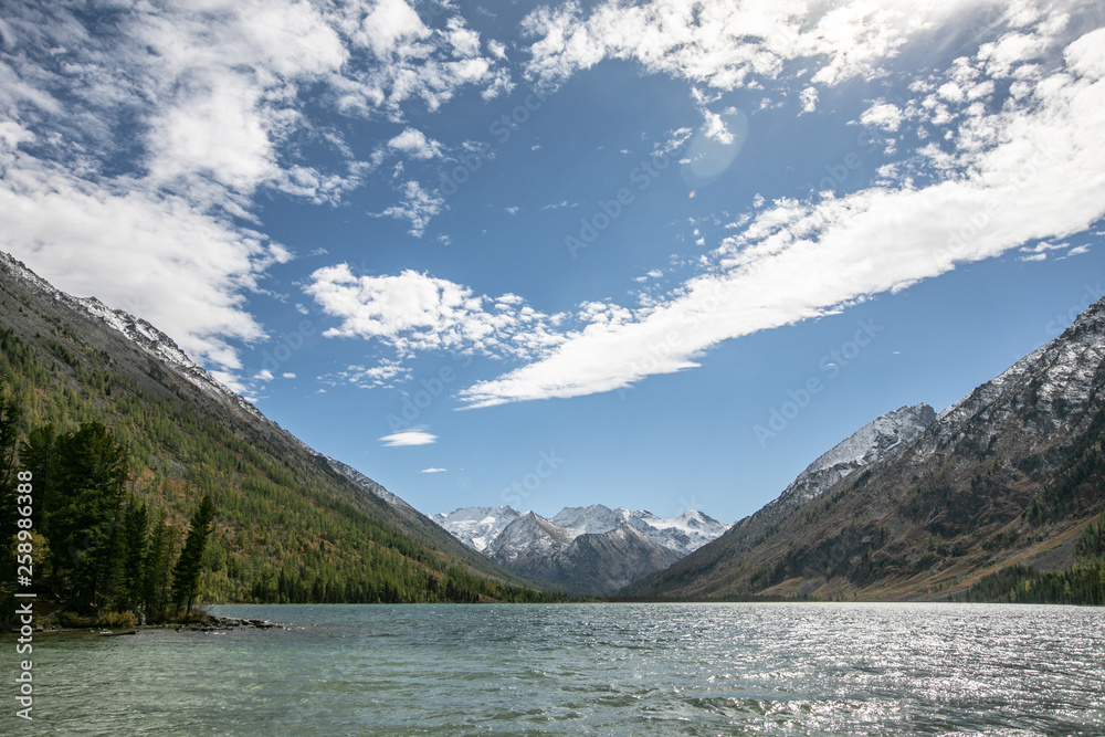 landscape with mountains, green trees and blue lake on a cloudy sky background landscape with mountains, green trees and blue lake on a cloudy sky background