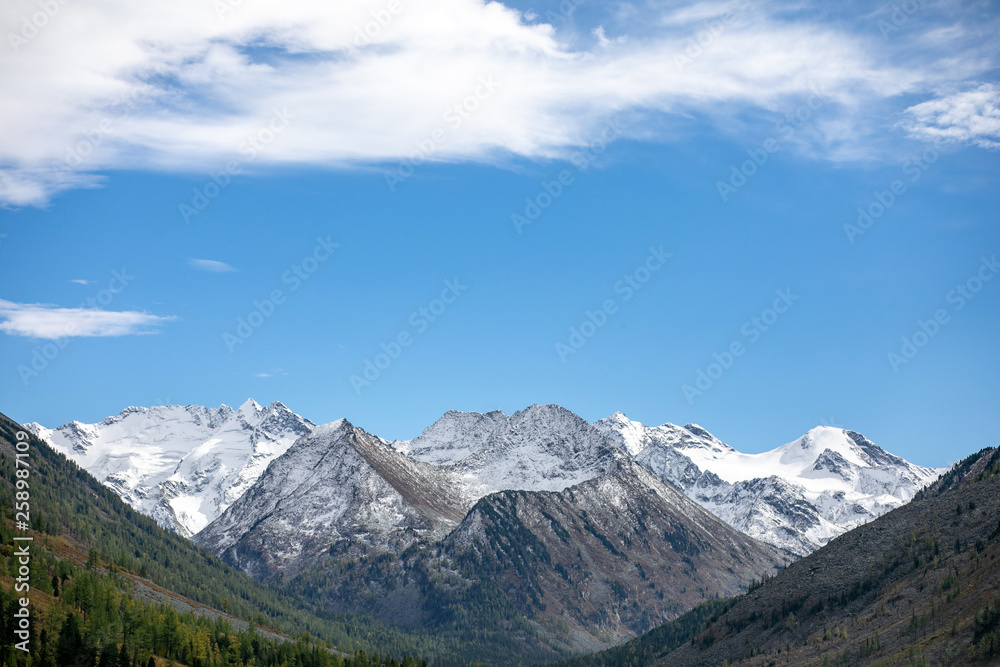 landscape with mountains, green trees and blue lake on a cloudy sky background Altai