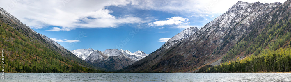 landscape with mountains, green trees and blue lake on a cloudy sky background Altai. Panorama