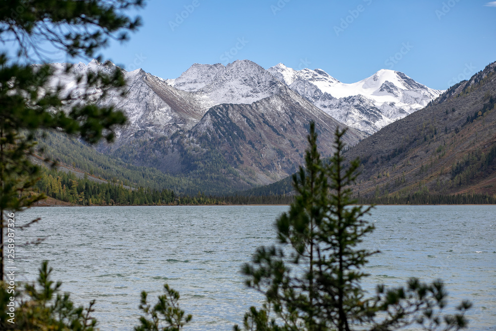 landscape with mountains, green trees and blue lake on a cloudy sky background Altai