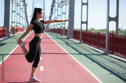 Strong fitness woman stretching at the pedestrian bridge before work out. Empty space © vpavlyuk