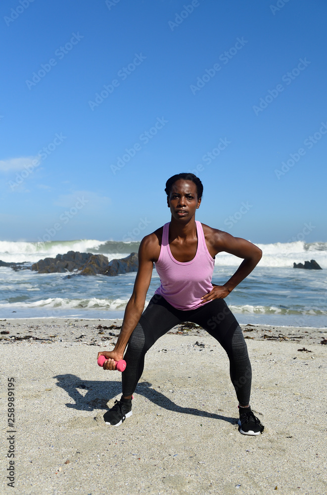 Woman doing fitness exercise with dumbbell on the beach Woman doing fitness exercise with dumbbell on the beach