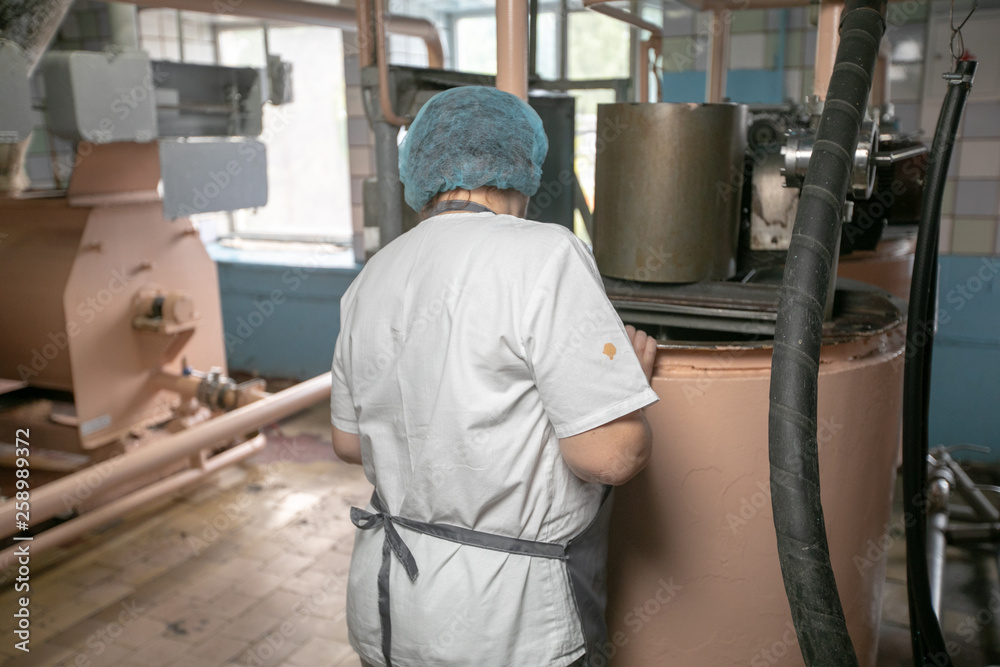 woman baker at the bread factory. Woman in uniform makes bread. Capacity for the dough.