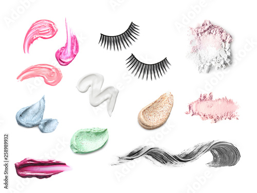 Set with swatches of lipsticks, eye shadows, scrubs, mascara and false eyelashes on white background, top view