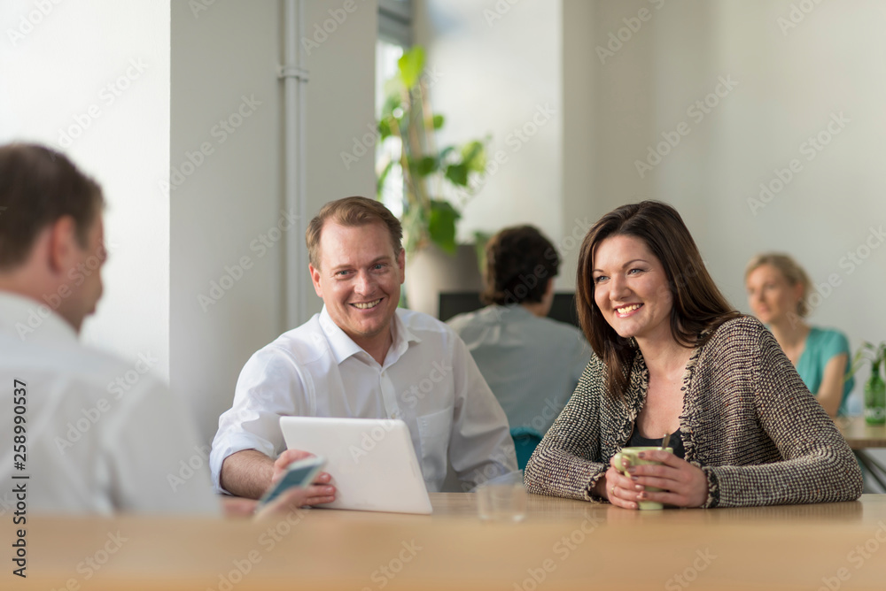 Happy colleagues looking at tablet in office Happy colleagues looking at tablet in office