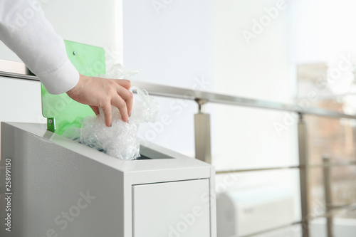 Young woman throwing plastic film in metal bin indoors, closeup with space for text. Waste recycling