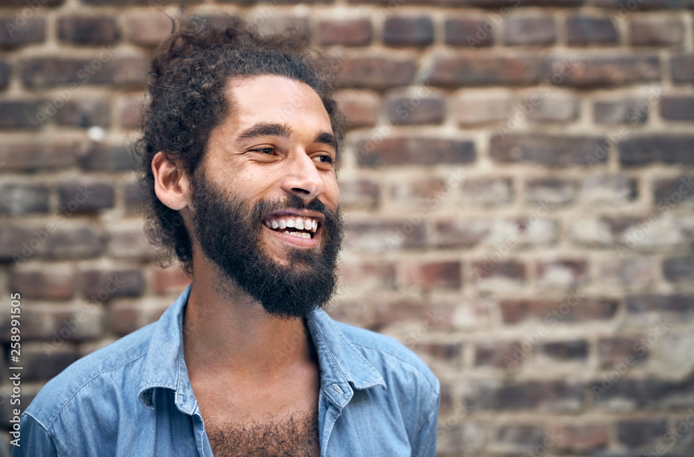 Portrait of a laughing young man in front of a brick wall Portrait of a laughing young man in front of a brick wall