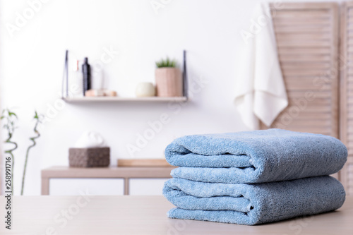 Stack of fresh towels on table in bathroom. Space for text