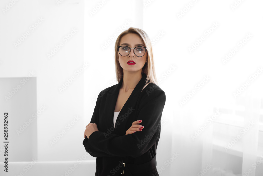 business, style and people concept. Serious blonde businesswoman with red lipstick, student or secretary in eyeglasses near window indoor business, style and people concept. Serious blonde businesswoman with red lipstick, student or secretary in eyeglasses near window indoor