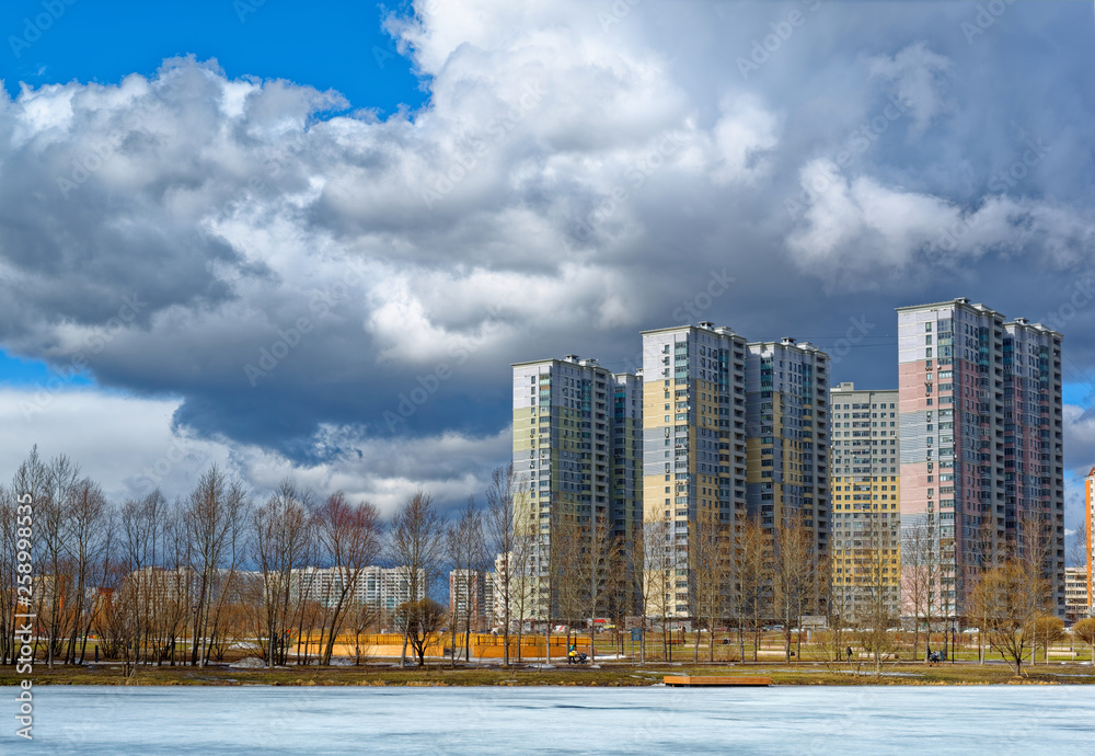 Fototapeta premium Urban houses and sky with clouds reflected in puddle from melting snow on street in day