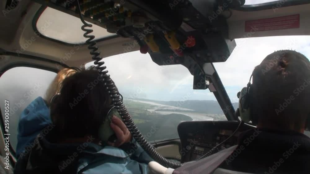 Passengers and pilot in cockpit helicopter window in New Zealand. View ...