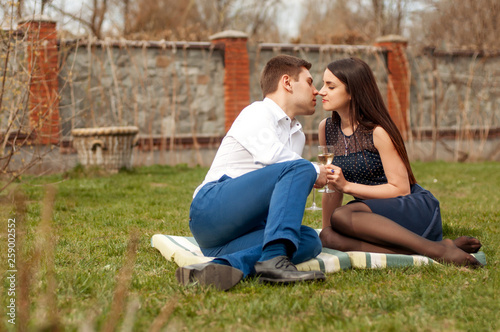 Excited romantic married couple are kissing and drinking wine outdoor in the garden