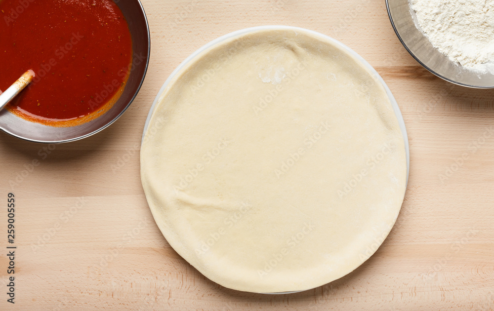Pizza preparation. Raw pizza base and sauce in bowl Pizza preparation. Raw pizza base and sauce in bowl