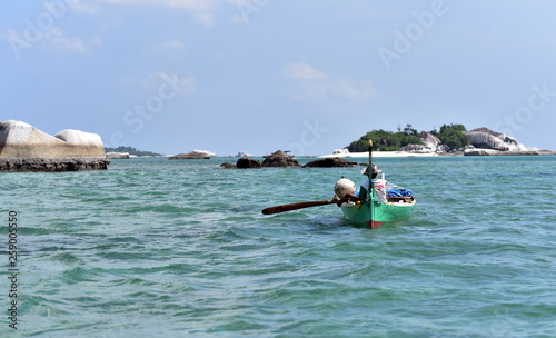 A fisherman paddles his boat out to sea, Tanjung Binga Beach, Belitung Island, Indonesia