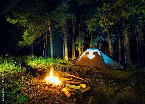 tent with a man and a woman in the woods in the evening by the fire