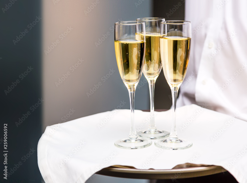 Waiter serving champagne glasses on a tray in a restaurant. Anniversary celebration concept. Waiter serving champagne glasses on a tray in a restaurant. Anniversary celebration concept.