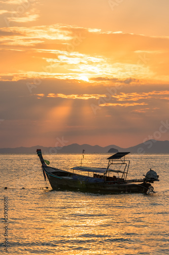 Golden sun rays and local empty thai long-tail boat under them in sea water at beautiful orange sunset © evgenydrablenkov