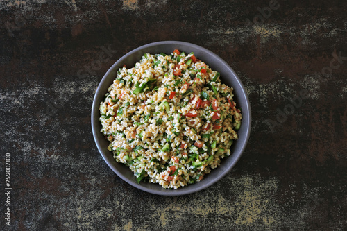 Arabic salad tabbouleh in a bowl. Middle Eastern cuisine. Healthy salad with bulgur, parsley and vegetables. Vegan salad with bulgur. Tabouli salad