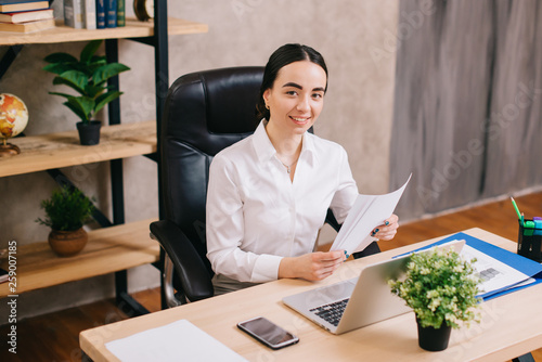 Young happy woman with documents in office