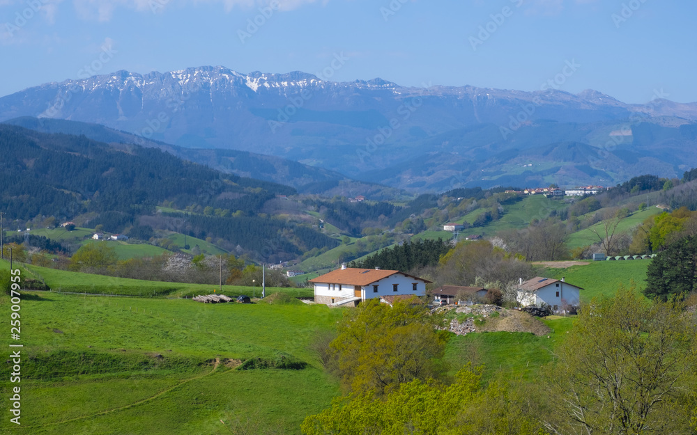 landscape view of green meadows mountains and a small farm, Basque Country, Spain