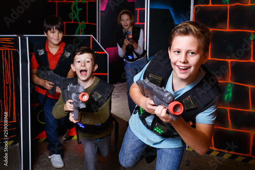 Portrait of preteen boy with laser gun having fun on dark lasertag arena