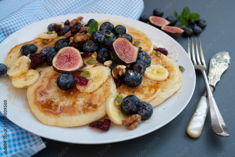 Pancakes with blueberries, mint, fruits and honey for breakfast - homemade healthy food. Breakfast idea.