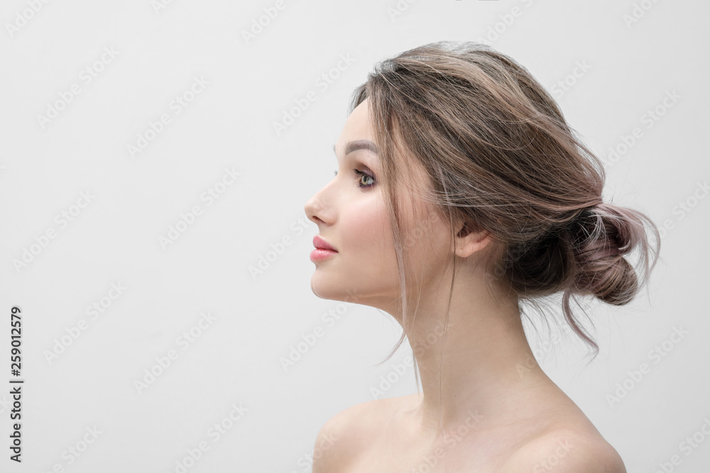 Beauty portrait of a young beautiful blonde woman, with bare shoulders in profile. Light gray background and copy space. Beautiful plump red lips. Beauty portrait of a young beautiful blonde woman, with bare shoulders in profile. Light gray background and copy space. Beautiful plump red lips.